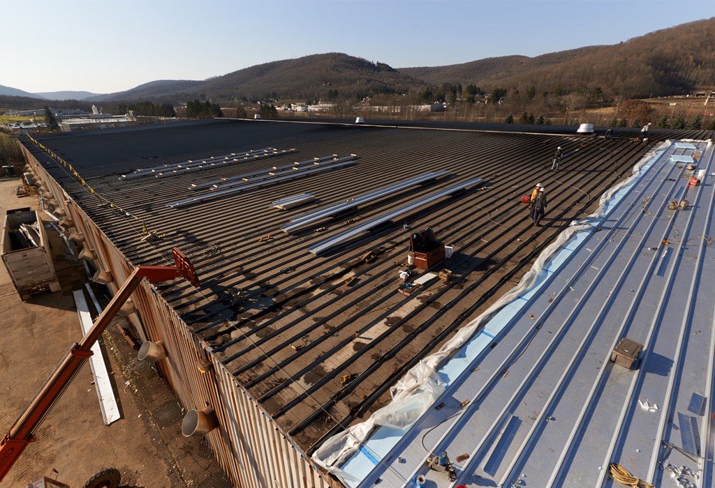 Aerial photo of a Phalen ReRoofing project in process, overlaying a new metal roof over the existing worn roof.